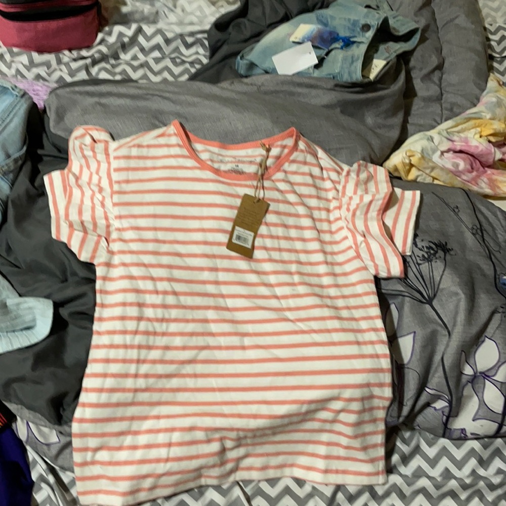 It is a tee shirt with pink and white stripes on it and has ruffles on the shirt